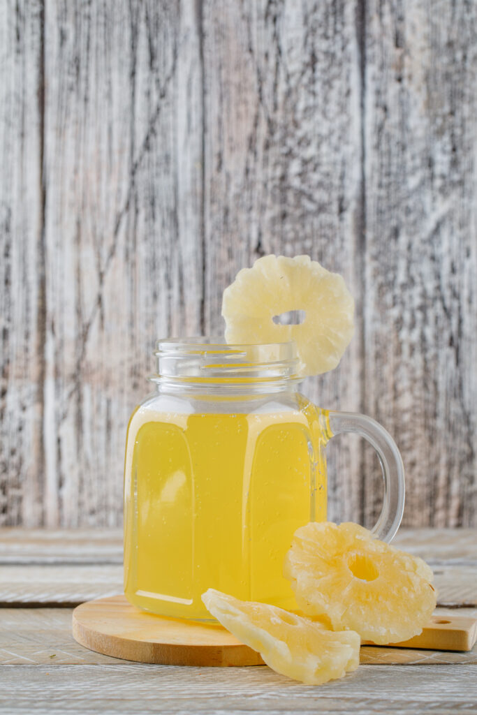 Dried pineapples with juice on wooden and cutting board background, side view.