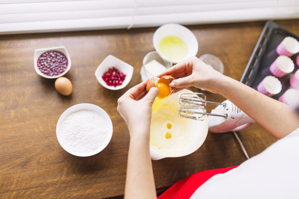 Detailed view of the process of making strawberry shortcake ice cream, featuring fresh strawberries, cream, and cake ingredients on a kitchen counter.