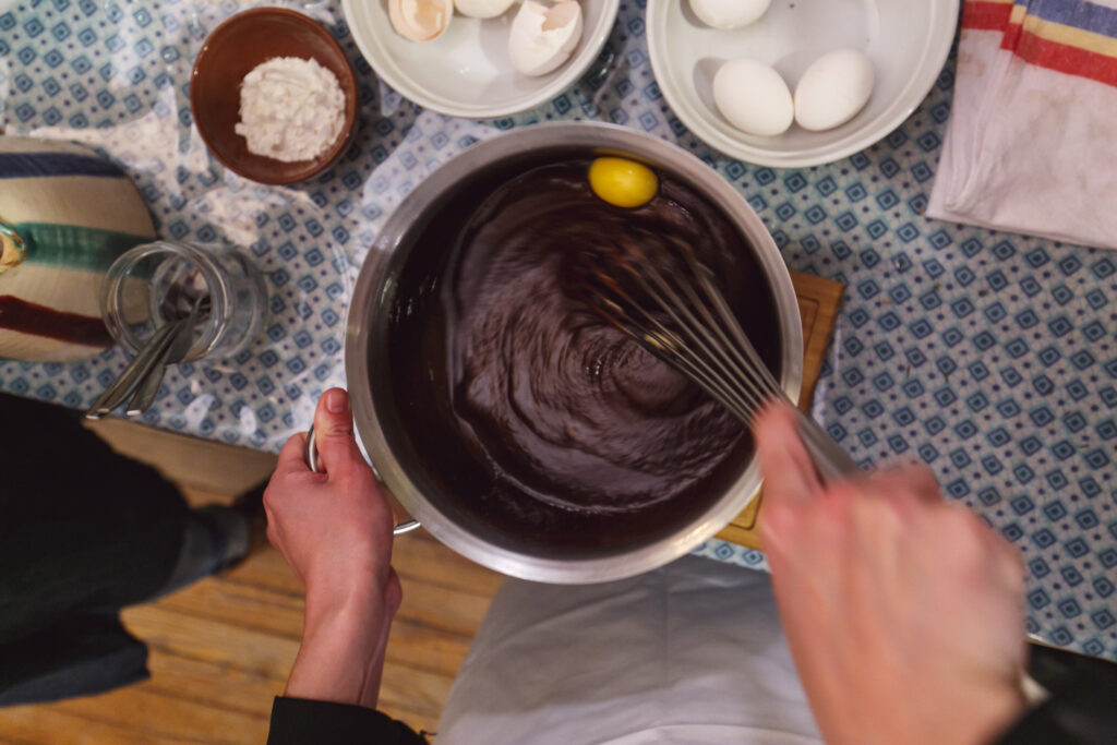 Detailed step-by-step process of baking a Nutella cake, featuring ingredients and baking tools spread on a kitchen table, perfect for recipe tutorials.