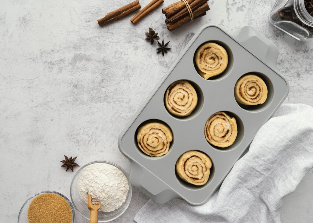 Top view of essential baking ingredients for cinnamon rolls arranged neatly on a wooden table.